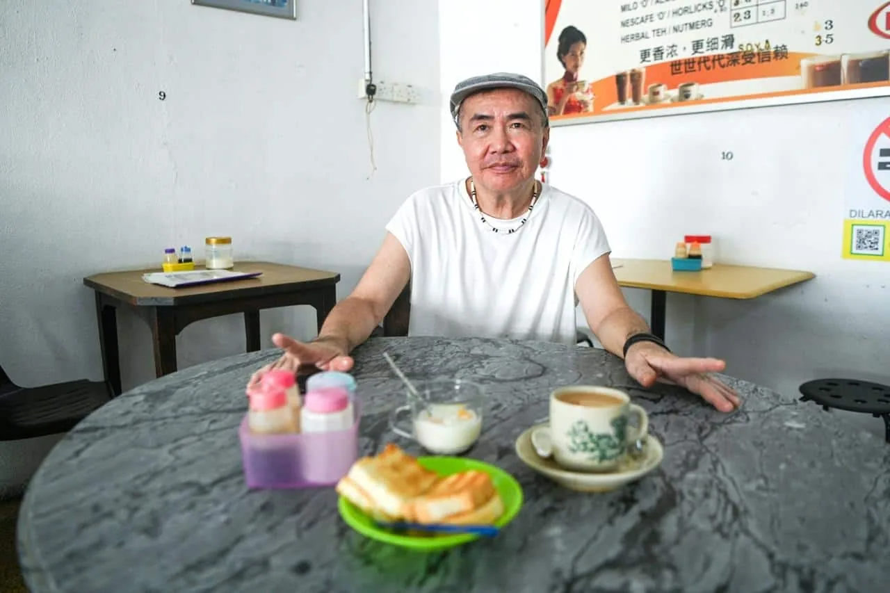Gary Tan at a marble-top table with a cup of Hainanese coffee and kaya toast. Photo: Siew Chia En/Buletin Mutiara